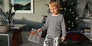 Billede af dreng med en julegave i hånden foran et juletræ